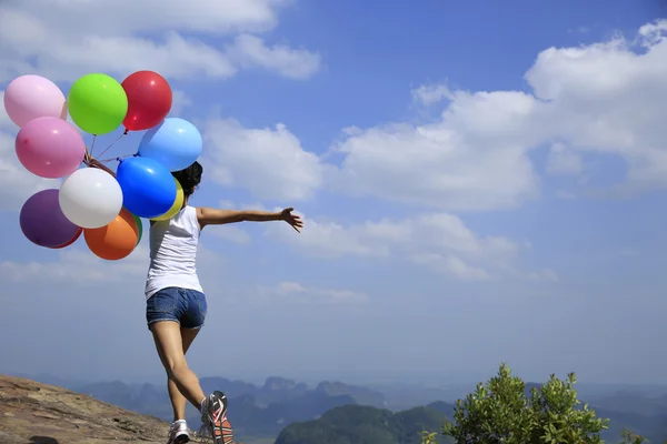Young woman running with colorful balloons