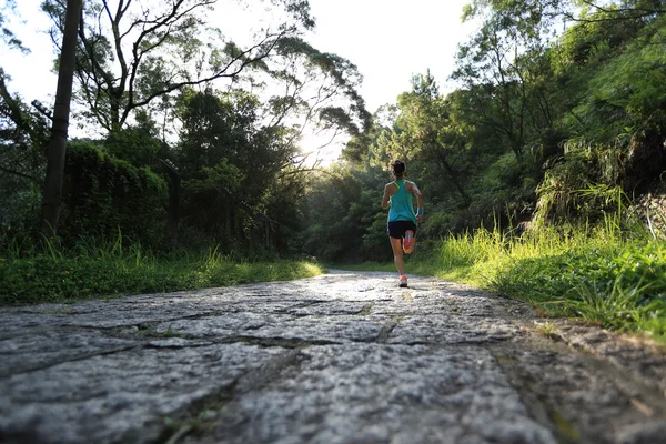 Female athlete running on forest trail.