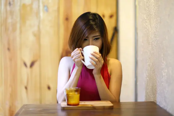 Pretty young woman sitting in the cafe and drink coffee