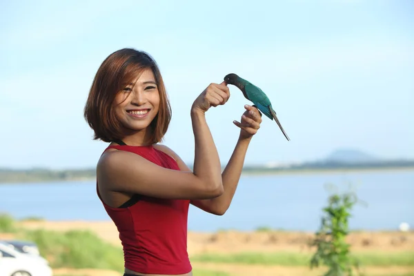 Pretty woman pose and smile with green bird
