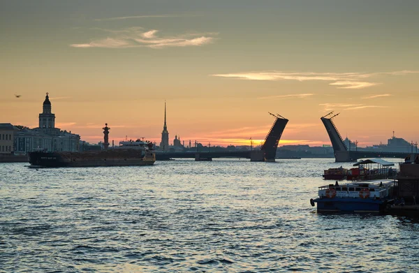 Russia, Saint-Petersburg, 03 July 2016: Closing of Palace Bridge at sunrise, the Peter and Paul Fortress Spike in the orange sky, Rostral colomn, ships, boats, the traffic beginning, sun,