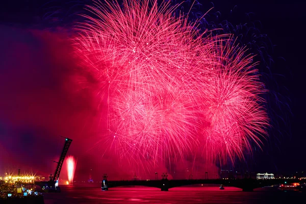 Russia, St. Petersburg, 20.6.2015: Fireworks on the Neva River on a holiday SCARLET SAILS diluted Troitsky Bridge, Rastralnye colony on the Spit of Vasilyevsky Island, a lot of people on the Palace Embankment, water flashes red, white night, holiday