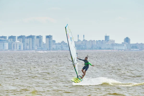 Russia, St. Petersburg, 07.04.2015: prorider Yegor Popretinsky, rus11, Russian champion in windsurfing performs a trick SHAKA, against the backdrop of the city of St. Petersburg Marine Port, ferry ships, the Gulf of Finland