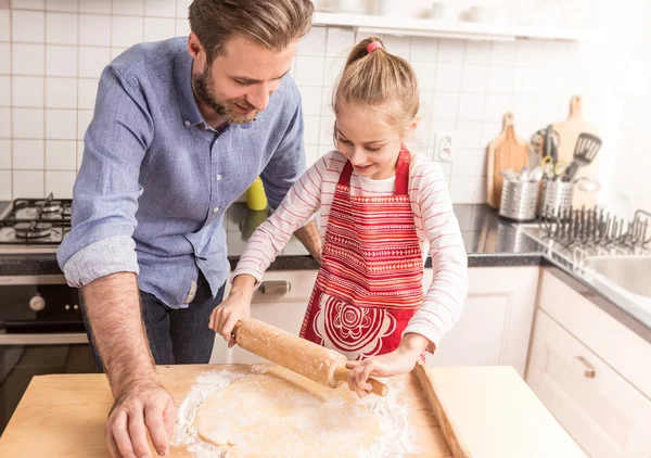 Happy father and daughter rolling out cookie dough in the kitche