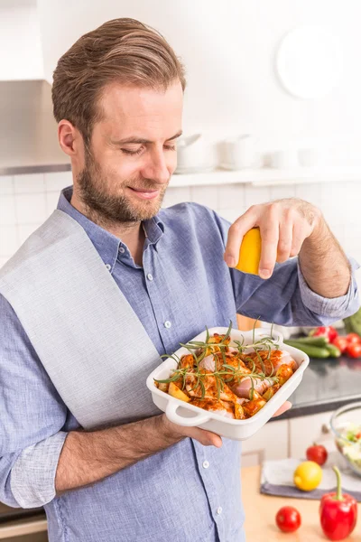 Man or chef holding roasting dish with raw chicken drumsticks