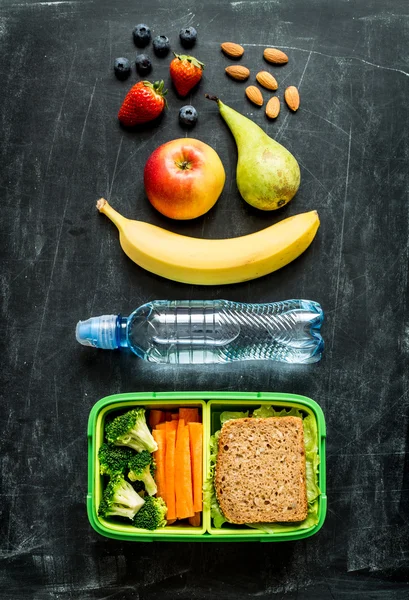 School lunch box with sandwich, vegetables, water and fruits