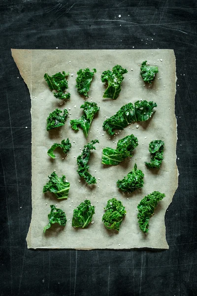 Kale bits on baking paper - preparing kale chips