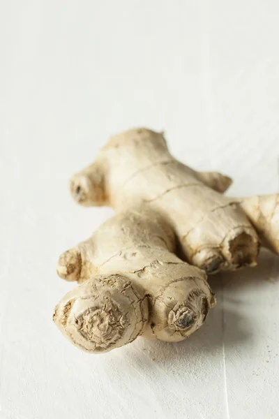 Fresh ginger root on white rustic wooden table