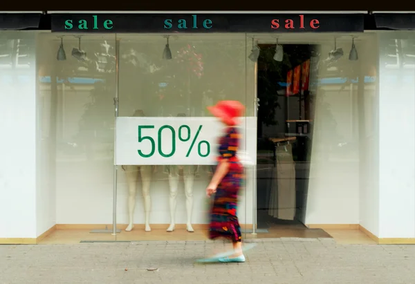 Sale signs in the shop window. Blurred figure of a woman