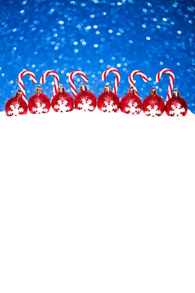 Christmas red balls in snow on blue glitter background