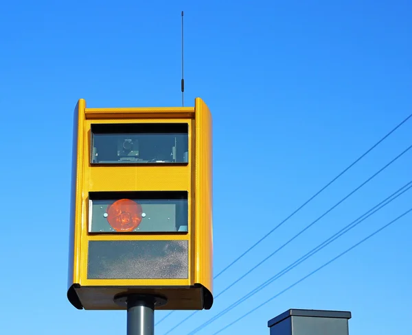 A traffic speed monitoring camera, against a bright blue sky.