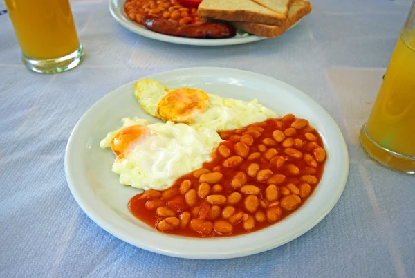 Full English cooked breakfast with bacon, sausage, fried egg and baked beans.