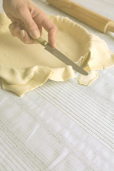 Cutting raw dough at the edges of the mold