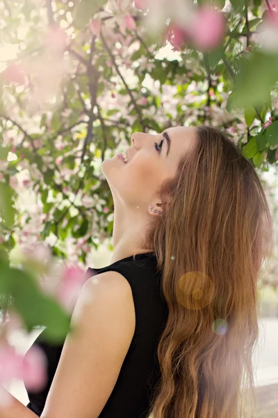 Woman in spring blossom. Young naturally beautiful woman near the blooming tree in spring time. Eco beauty and health concept.