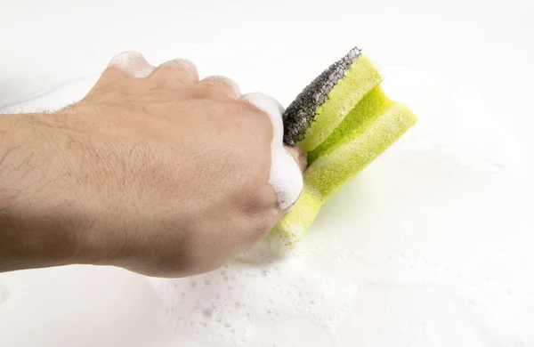 Hand holding a soapy sponge with scrub on a white background