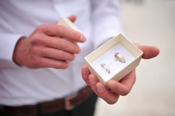 Groom holding wedding rings in a box