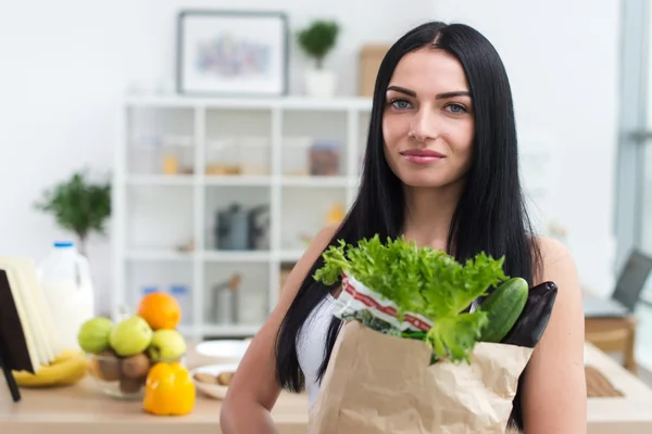 Female cook holding bag full of greens