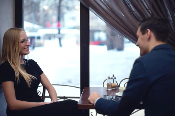 Two young businessmen during lunch in the cafe have a small talk smiling