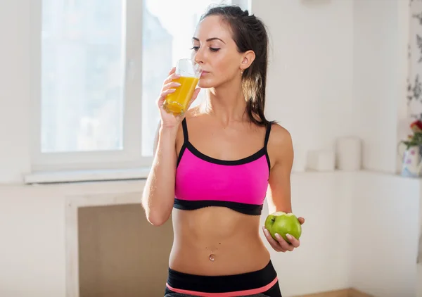 Gorgeous young athletic sportive woman in sport outfit drinking fruit juice after the training
