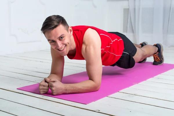Sportive man doing plank core exercise training back press muscles looking at camera with smile concept gym sport sportsman crossfit fitness workout strenght power