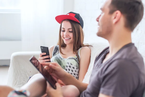 Friends girl with cup of coffee and guy sitting on sofa at home in summer jeanswear street urban casual style talking, having fun