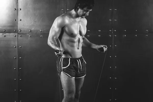 Fitness model muscular man with skipping jumping rope around his neck copy space healthy lifestyle bodybuilding concept black and white