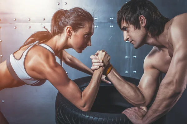 Athlete muscular sportsmen man and woman with hands clasped arm wrestling challenge between a young couple Crossfit fitness sport training lifestyle bodybuilding concept.