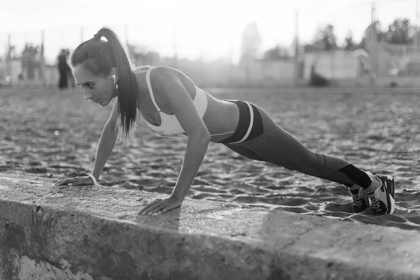 Fitness woman doing push ups Outdoor training workout summer evening. Concept sport healthy lifestyle.