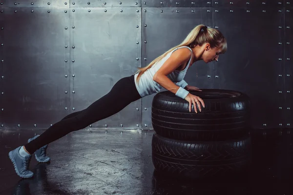 Sportswoman. Fit sporty athlete woman doing push ups on tire strength power training concept crossfit fitness workout sport and lifestyle side view