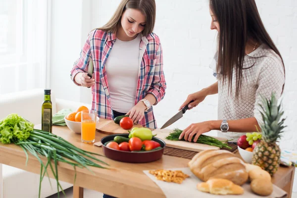 Two girls friends preparing dinner in a kitchen concept cooking, culinary, healthy lifestyle.