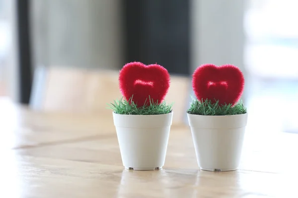 Flowerpot with artificial heart placed on table.