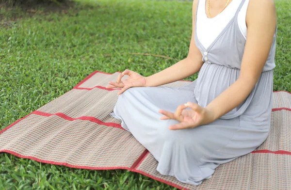Pregnant women sitting meditation in the park.