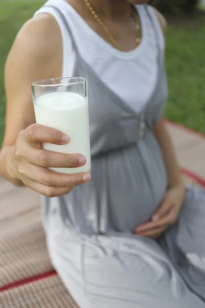 Pregnant women have a glass of Milk in hand.