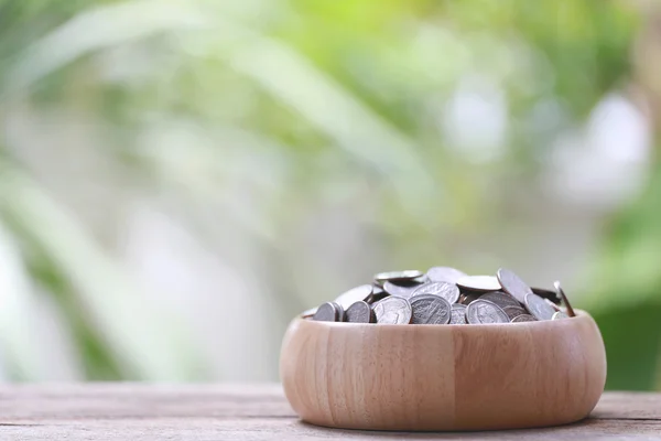 Silver coin in wooden bowl is placed on a wood floor with colorf