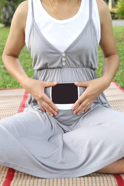 Pregnant women show ultrasound film picture on her belly.