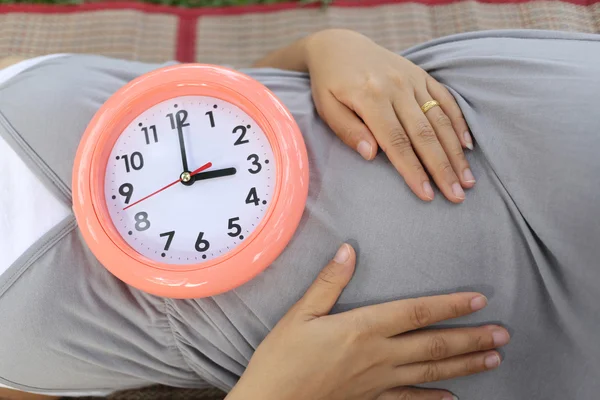 Pregnant women show clock on her belly to tell the time.