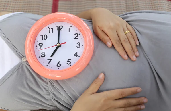 Pregnant women show clock on her belly to tell the time.