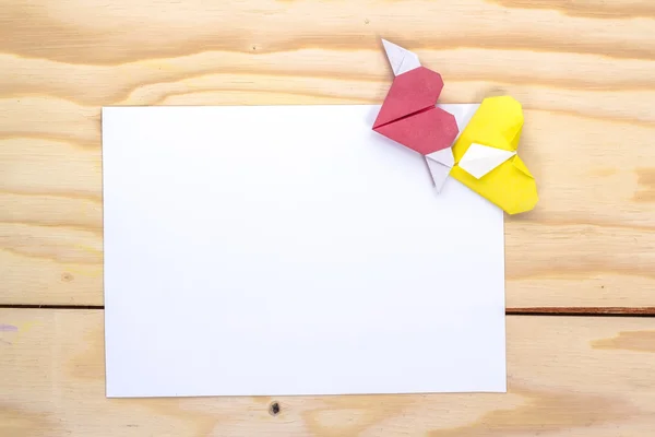 Valentines card with origami yellow and red hearts on wooden table