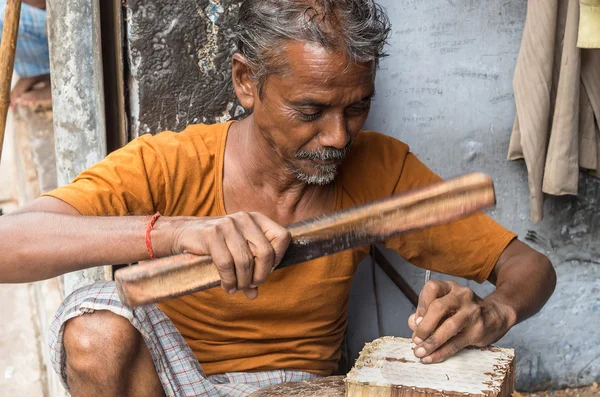 A craftsman carving a wooden printing block for textile block pr