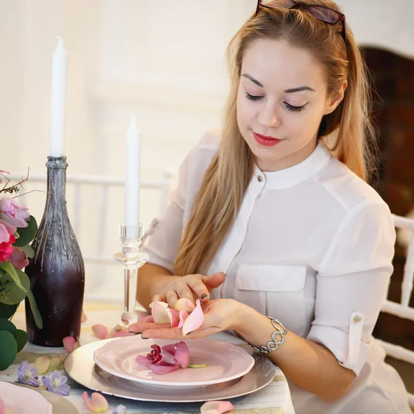 Young woman create a decoration. Decor and floral composition on a table.