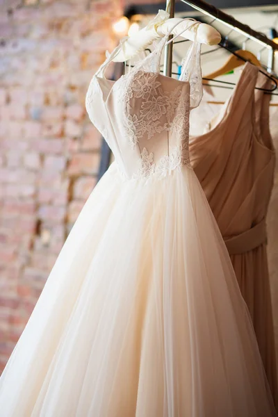 Closeup photo of beautiful wedding dress on a hanger in a loft space