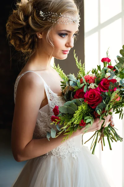 Beautiful bride in gorgeous luxury dress holding bouquet in a loft space. Modern wedding photo