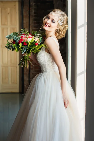 Beautiful bride in gorgeous luxury dress holding bouquet in a loft space. Modern wedding photo