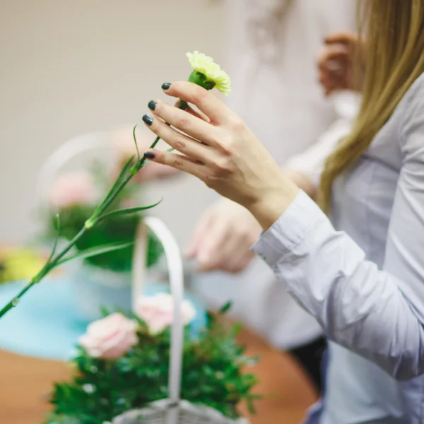 Floral workshop - florist makes a bouquet in a basket. Students florists work together.