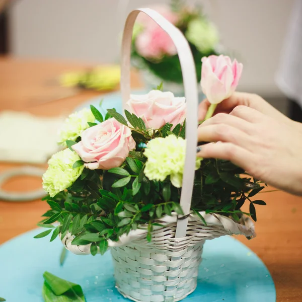 Floral workshop - florist makes a bouquet in a basket. Students florists work together.