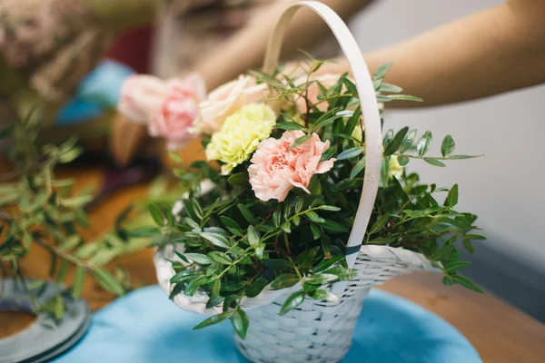 Floral workshop - florist makes a bouquet in a basket. Students florists work together.