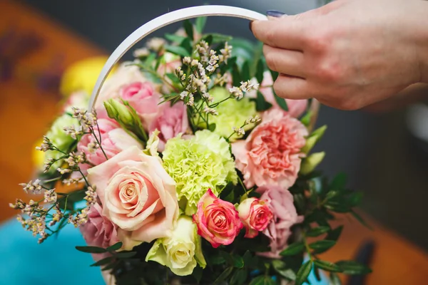 Floral workshop - florist makes a bouquet in a basket. Students florists work together.