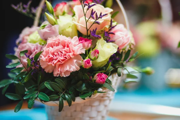 Florist workplace: pretty bouquet in a basket on a background of flowers and accessories. soft focus