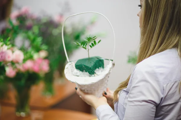 Floral workshop - florist makes a bouquet in a basket. Students florists work together.