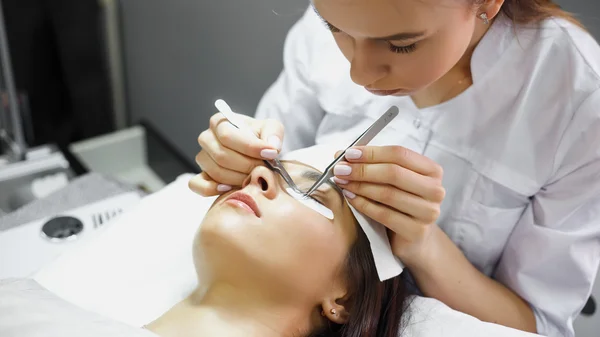 Eyelash extension procedure - master and a client in a beauty salon